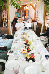 Wedding table setting. Festive table with white tablecloth. guests sit at the table. on the table are fruits, cheeses, glasses. cheese and wine tasting