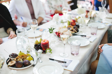 Wedding table setting. Festive table with white tablecloth. guests sit at the table. on the table are fruits, cheeses, glasses. cheese and wine tasting