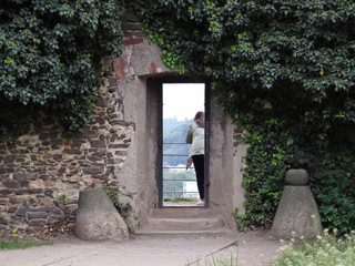 Woman Silhouette Standing behind Door Frame in Old Historic Wall with Plant