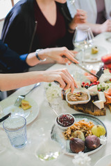 Wedding table setting. Festive table with white tablecloth. guests sit at the table. on the table are fruits, cheeses, glasses. cheese and wine tasting