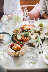 Wedding table setting. Festive table with white tablecloth. guests sit at the table. on the table are fruits, cheeses, glasses. cheese and wine tasting