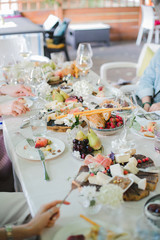 Wedding table setting. Festive table with white tablecloth. guests sit at the table. on the table are fruits, cheeses, glasses. cheese and wine tasting