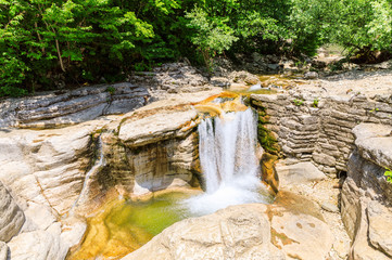 Okatse first canyon and small Kinchkha waterfall in the canyon of the river Okatse. Rest in Georgia. Rocky ledges of the mountain with green trees.
