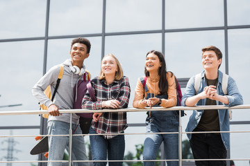 cheerful and happy teenagers smiling and looking away outside