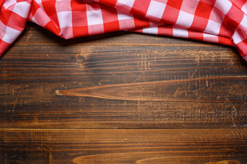 a checked gingham picnic tablecloth on old wooden table top view