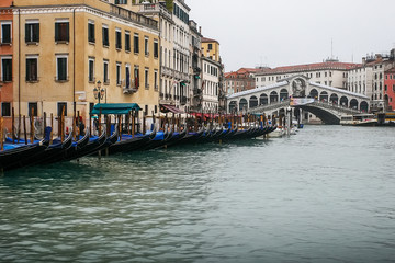 Gondolier on gondola on the Grand Canal in Venice, Italy. April 2012  View on Rialto bridge at Rainy day.