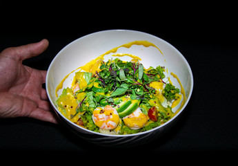 a tasty prawn and avocado salad being presented by a hand 