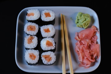 Sushi roll with seafood and soy sauce, wasabi and ginger. Sushi roll on a gray plate