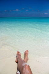 feet on the beach/woman sits on white sand beach and relaxes on paradise tropical Maldives beach.