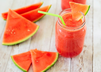 Watermelon smoothies in a glass filled with watermelon on top in a wooden background