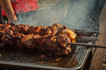 Barbecue fries in the coals. Meat and beef at the field kitchen festival. Fried meat on an iron tray on the table.