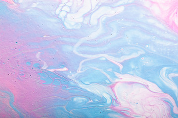 Abstract handmade composition made in the technique of fluid art. Bright art project in trendy pastel shades of pink and blue with white and silver lines and droplets interspersing.