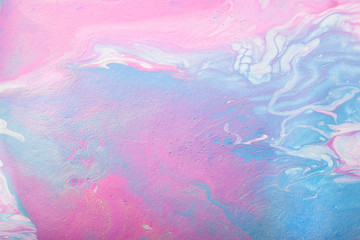 Abstract handmade composition made in the technique of fluid art. Bright art project in trendy pastel shades of pink and blue with white and silver lines and droplets interspersing.