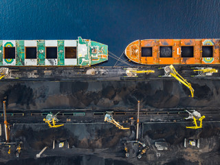Cranes loading coal Anthracite on bulk vessel ship in offshore cargo port. Aerial top view