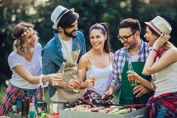 Young friends having fun grilling meat enjoying barbecue party.
