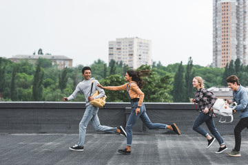 playful and happy teenagers running on roof and smiling
