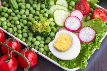 A set of vegetables with rice and egg: peas, asparagus, radishes, broccoli, lettuce, tomatoes. Black background