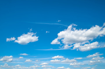 White fluffy clouds in the blue sky. Blue sky and large and small clouds in summer windy weather.