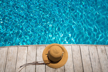 Fototapeta na wymiar Hat at the side of swimming pool, summer travel concept
