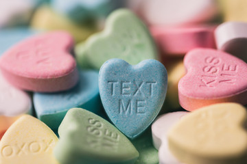 Close up of candy hearts with Valentine's messages on them.