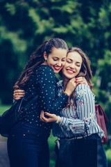 Fototapeta premium Two emotional happy woman friends hugging each other in the park