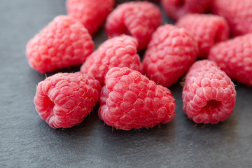 group fresh ripe raspberry on a dark stone background, natural berry with natural backlight on black spacing macro
