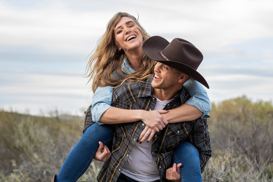 Western wear young couple giving piggy back ride and laughing