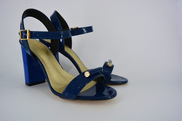 Elegant women's sandals from natural patent leather and zotoli insoles. Fashionable dark blue sandals with high, wide heels with a broom and gold clasps.