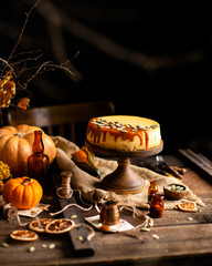 homemade tasty pumpkin orange cheesecake on wooden cake stand on rustic brown table