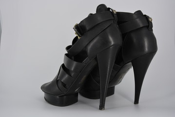 Sexy glamorous black women's sandals from genuine cowhide matte leather on high heels. Fashion women's shoes made of leather bands, ribbons with gold clasp on them.