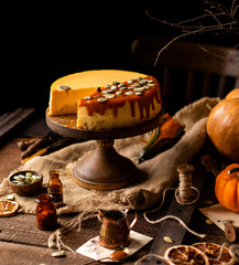 homemade tasty pumpkin orange cheesecake on wooden cake stand on rustic brown table