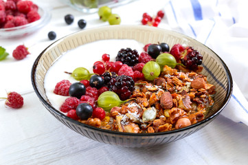 Yogurt, granola, fresh berries in a bowl on a white wooden background. Delicious and healthy breakfast. Proper nutrition. Dietary menu.