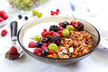 Yogurt, granola, fresh berries in a bowl on a white wooden background. Delicious and healthy breakfast. Proper nutrition. Dietary menu.