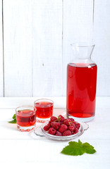 Raspberry liqueur in glass and fresh berries on a white background. Alcoholic flavored drink.