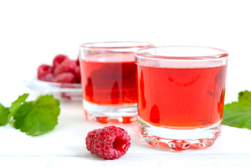 Raspberry liqueur in glass and fresh berries on a white background. Alcoholic flavored drink.