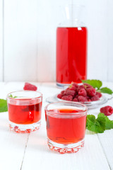 Raspberry liqueur in glass and fresh berries on a white background. Alcoholic flavored drink.