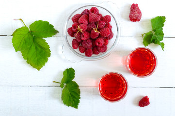 Raspberry liqueur in glass and fresh berries on a white background. Alcoholic flavored drink. The top view, flat lay