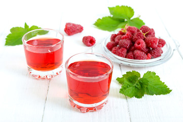 Raspberry liqueur in glass and fresh berries on a white background. Alcoholic flavored drink.