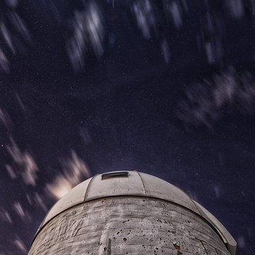 Long-exposure of clouds during starry night,  foreground observatory