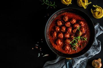 Meatballs in tomato sauce on the pan - black background