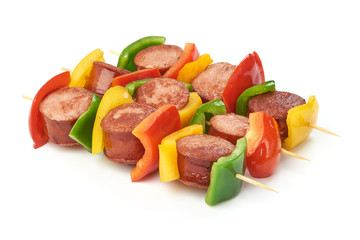 Skewers with pieces of grilled sausage and vegetables BBQ, close-up, isolated on white background