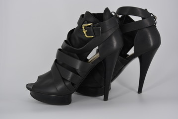 Sexy glamorous black women's sandals from genuine cowhide matte leather on high heels. Fashion women's shoes made of leather bands, ribbons with gold clasp on them.