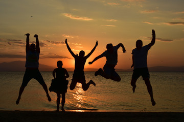 silhouette of friends jumping on beach during sunset time