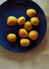 a pile of apricots on a blue plate.