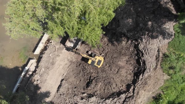 Excavator loading arriving dump truck tipper at excavation site aerial top view