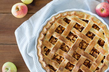 food, culinary and baking concept - apple pie and kitchen towel on wooden table © Syda Productions
