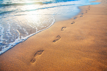 beach, wave and footprints at sunset time