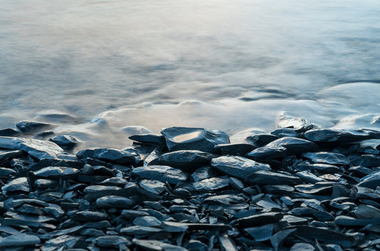 The water moving through the stones in a shore of a lake.