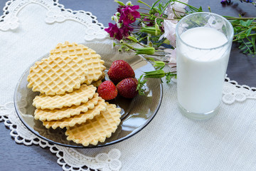 Healthy breakfast. Belgian waffles with milk and strawberry on white tablecloth. Selective focus