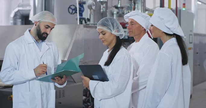 Group of bakery industry workers engineer explaining the plan of security for industrial machine old baker man and his assistances listing very concentrated